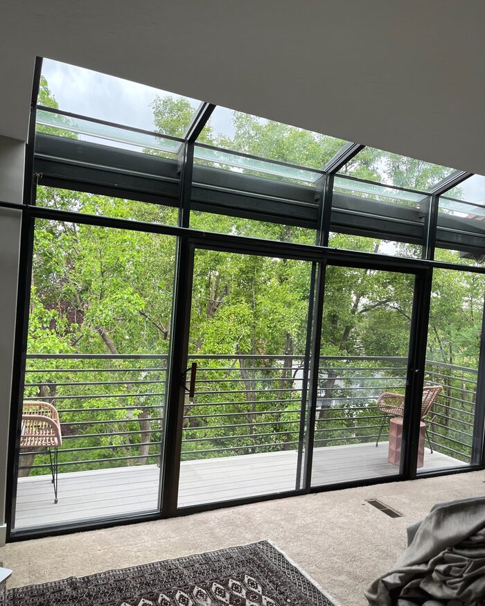 A finished wall of clean interior windows facing a wooded balcony.