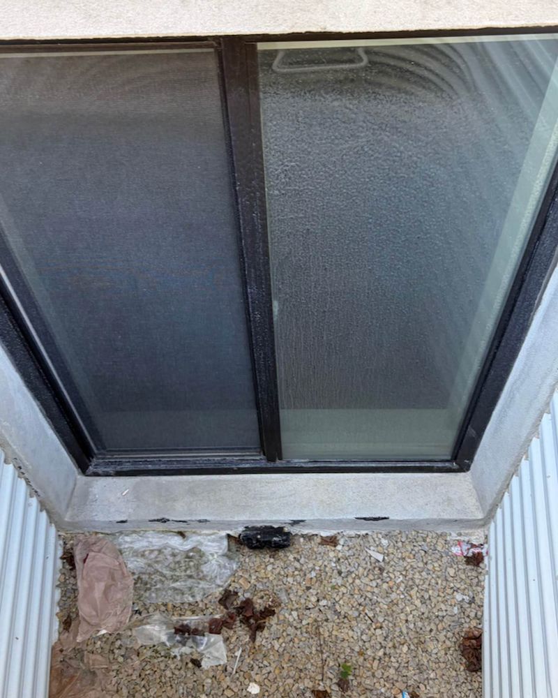 Before hard water removal, the window glass is clouded by heavy white mineral buildup.